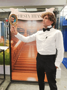 a man in a tuxedo holds a mirror in front of a fiesta titans sign