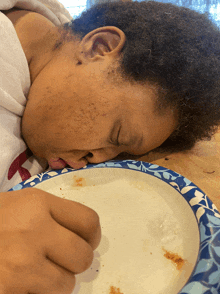 a child is laying on a table with his head on a plate