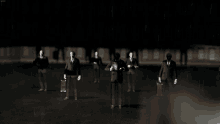 a group of men in suits are standing in a dark room