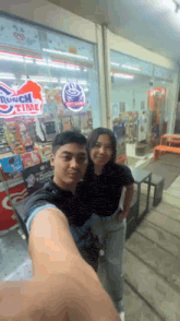 a man and a woman are posing for a picture in front of a city cafe sign