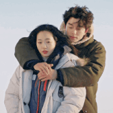 a man is hugging a woman who is wearing a white jacket with the word columbia on it