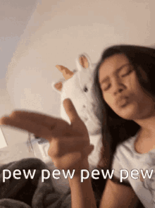 a woman is giving the middle finger in front of a stuffed unicorn .