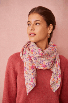 a woman is wearing a pink sweater and a scarf around her neck