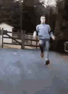 a man in a blue shirt and jeans is running down a street .