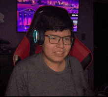 a young man wearing glasses and headphones is sitting in a gaming chair