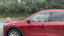 a red car is parked on the side of the road in front of trees