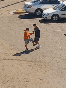 a man in an orange hoodie is standing next to a man in a black shirt