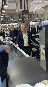 a man in a suit stands at a counter in front of a titanyc store