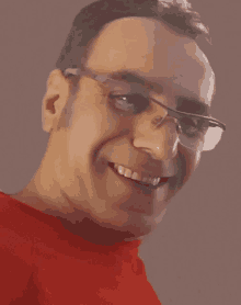 a smiling man wearing glasses and a red shirt