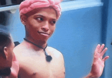 a shirtless man wearing a pink turban and a black necklace