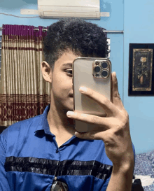 a man in a blue shirt takes a picture of himself with his phone