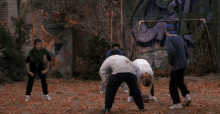 a group of people are playing a game of soccer in front of a wall with graffiti on it that says u.s.