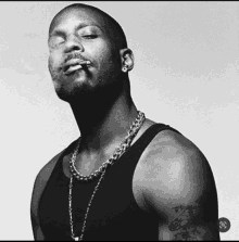 a black and white photo of a man wearing a tank top and a chain around his neck