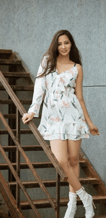 a woman in a white dress and white boots is standing on a set of stairs