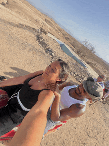 a man in a white tank top holds a woman in a black top