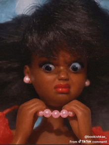 a doll with a necklace of pink beads has a tiktok comment