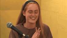 a woman is smiling in front of a microphone