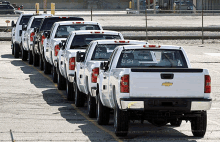 a row of white chevrolet trucks are parked in a lot