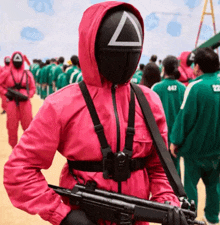 a man in a triangle mask holds a gun in front of a crowd