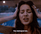 a woman with her hands on her head is saying you betrayed me