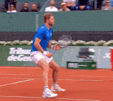 a man in a blue shirt is holding a tennis racquet on a tennis court in front of a tribune de ger