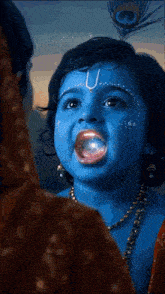 a little girl with blue paint on her face and a peacock feather in her hair