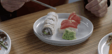 a person eating sushi with chopsticks on a plate