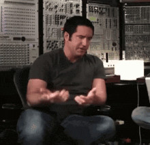 a man in a black shirt is sitting in a chair with his hands out