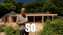 a man is standing in front of a house that is under construction and the word so is on the ground