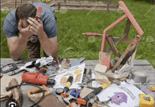 a man sits at a messy table with tools and a sign that says " keep it clean " on it