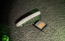 a green shoe is laying on a green carpet next to a small calculator