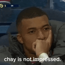 a man is sitting in a chair with his hand on his chin and the words `` chay is not impressed '' .