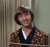 a young man is tied up with a rope and smiling for the camera
