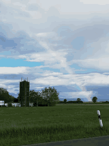 a rainbow is visible over a field with a tower in the background