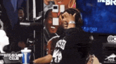 a man wearing a black shirt that says usher is sitting in front of a microphone