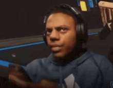 a man wearing headphones and a blue hoodie looks at his phone .