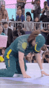 a man in a green and yellow outfit with australia on it is kneeling down in front of a crowd