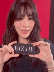 a woman holding a sign that says bazaar in her hands