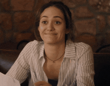a woman in a striped shirt is smiling and holding a piece of paper with the letter s on it