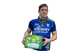 a man in a blue kerry group jersey holds a green box