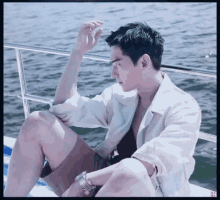 a man in a white shirt sits on a boat near the water