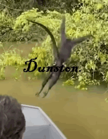 a man in a boat is looking at a crocodile in the water and the name dunston is on the bottom right