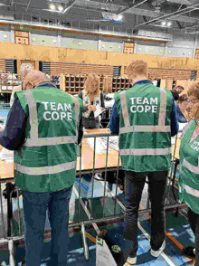 a group of people wearing green vests with the word team cope on them .