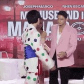 a man in a pink jacket is standing next to a woman in a polka dot outfit .