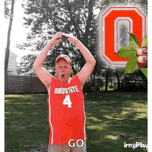 a man wearing an ohio state jersey with the number 4 on it stands in front of an ohio state logo