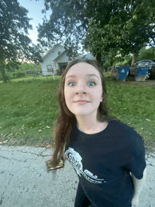 a girl wearing a black shirt with the word ghost on it stands in front of a house