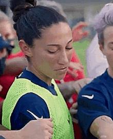 a female soccer player is standing on a field with her eyes closed and a bun in her hair .