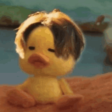 a stuffed duck with a wig on is sitting on a bed .