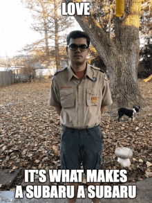 a boy scout is standing in front of a tree with a meme that says love it 's what makes a subaru