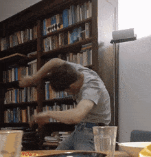 a man is dancing in front of a bookshelf that has a book titled ' a brief history of the world '